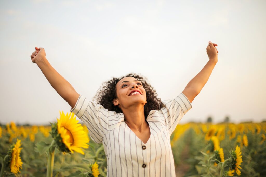 femme dans un champ qui lève les bras en l'air et respire